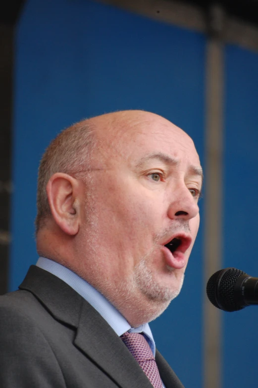 a man standing at a microphone with his hands open