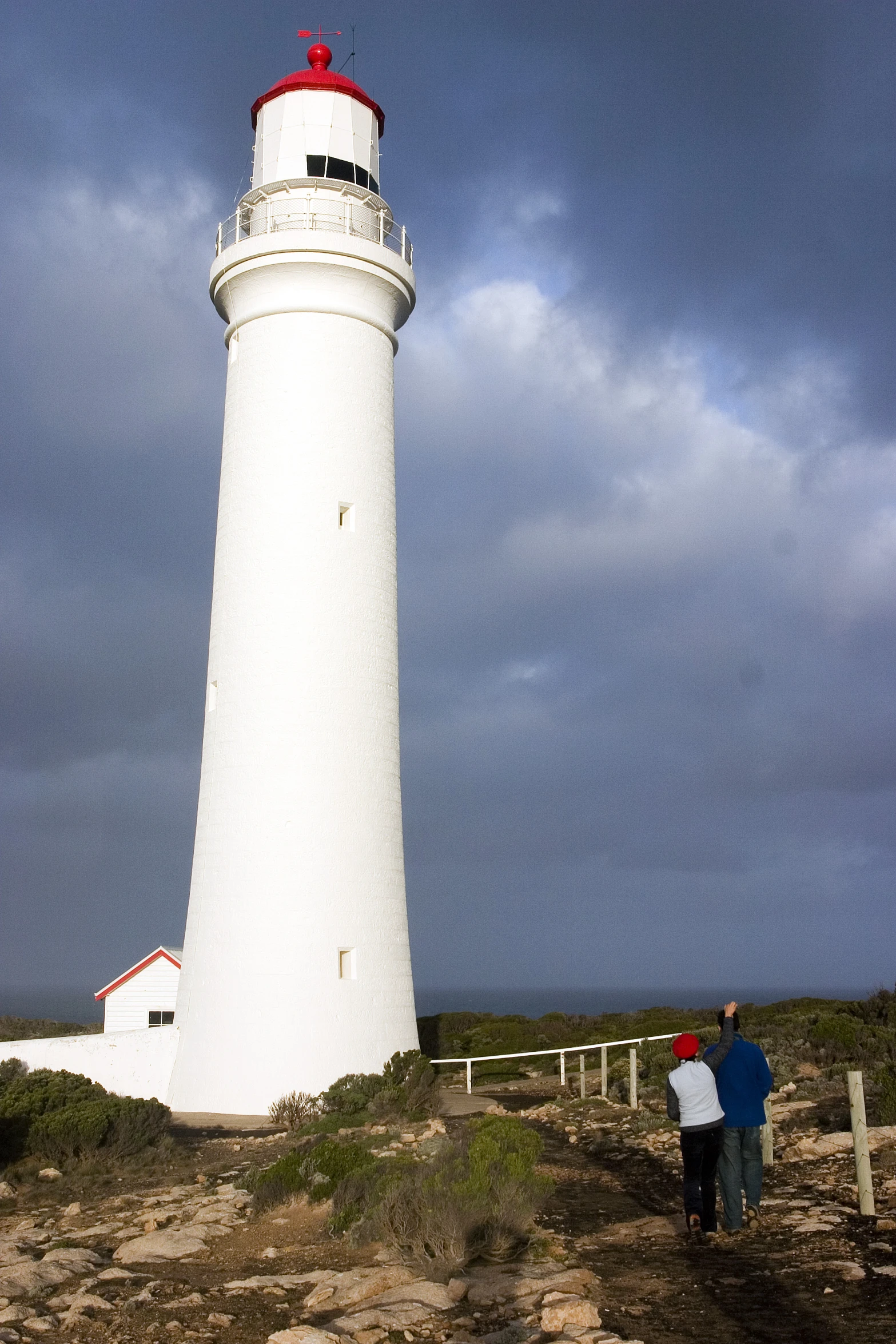 people walking up the side of a white lighthouse