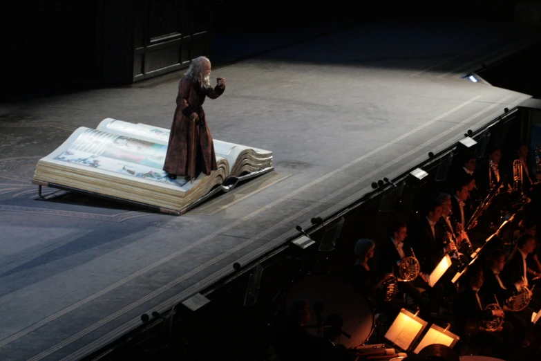 a large crowd is watching a man stand next to a giant book