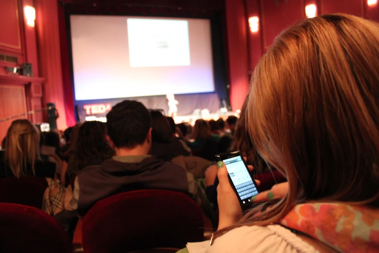 a woman looking down at her phone in the front of a crowd