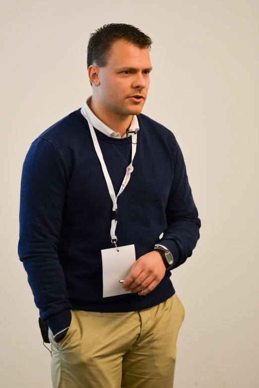 a man in a sweater and tie is holding a piece of paper