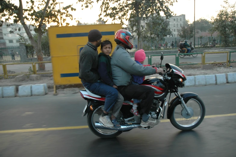 three people on a motorcycle riding down the road