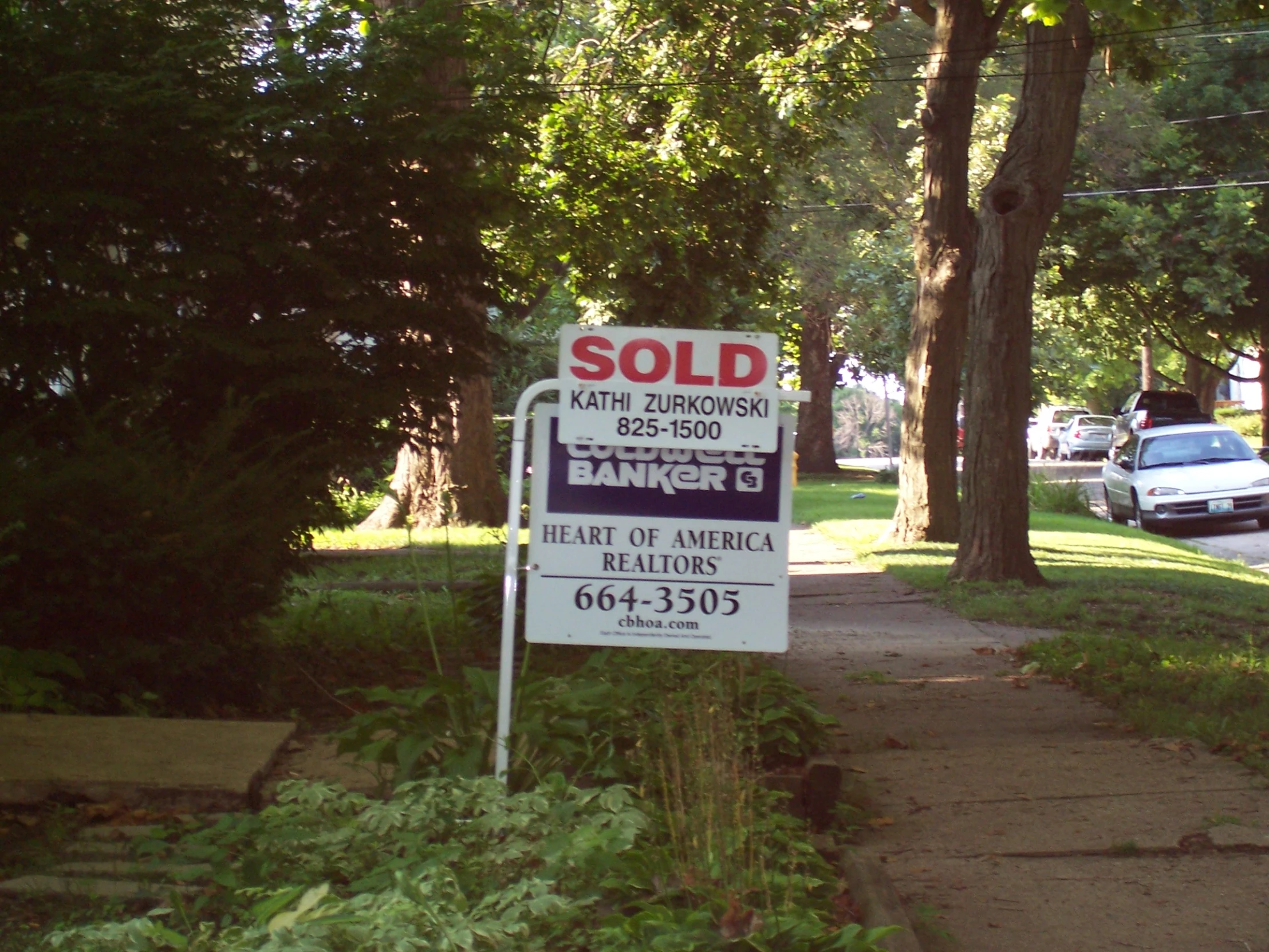 a house with a sold sign next to a garden and sidewalk