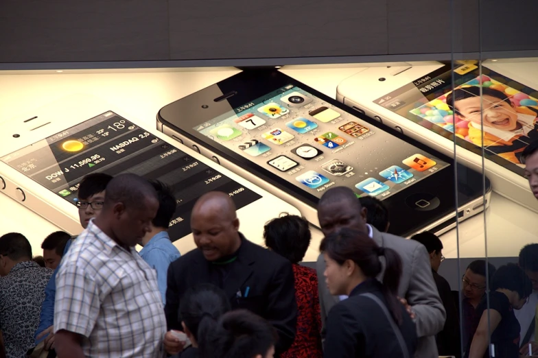 people standing around looking at several phones on display