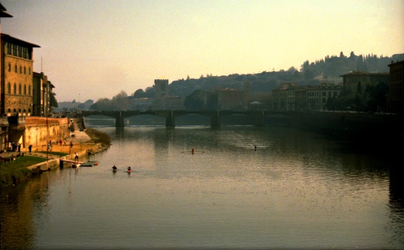 an old bridge crosses a river with people on it