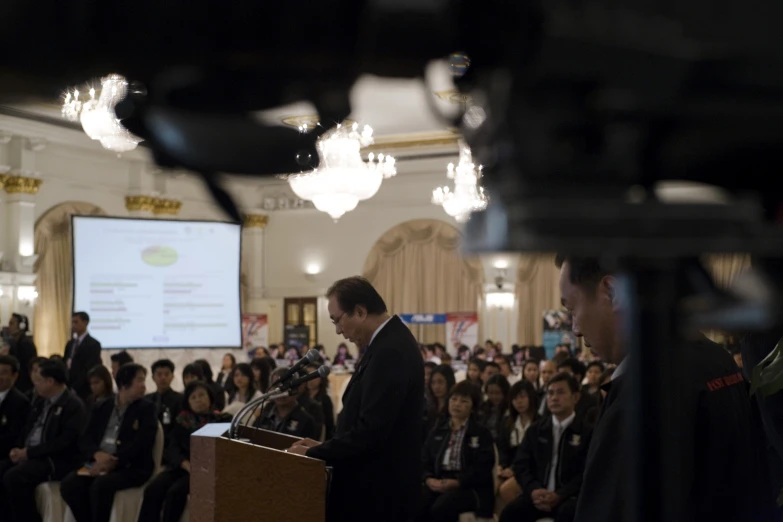 a large group of people in the background watching a speaker