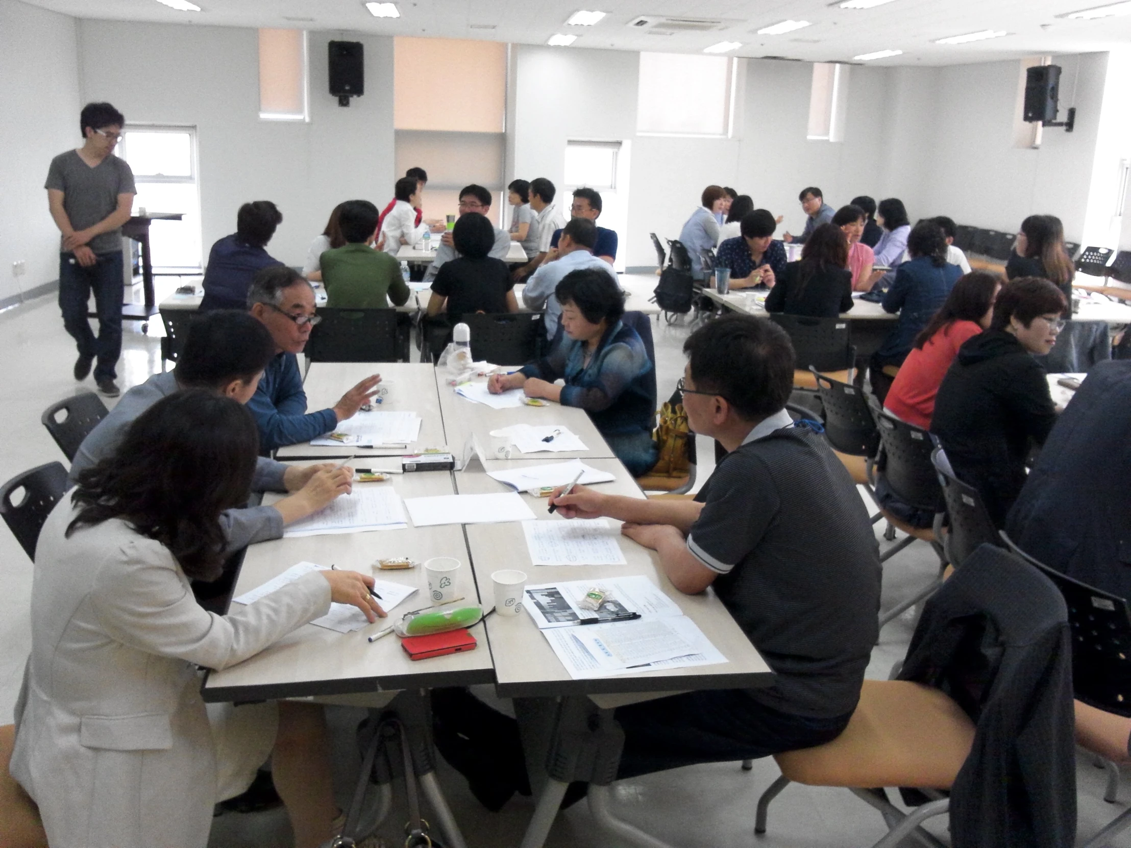 group of people sitting at white tables working on paperwork