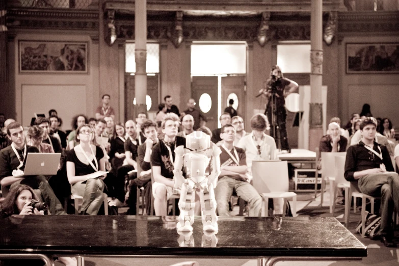 a crowd of people standing and sitting at tables in a building