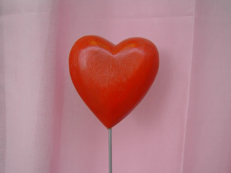 a large heart shaped lollipop on top of a small stick