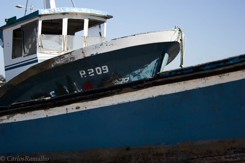 the back of a boat is torn apart and sitting on top of a rusted piece of iron