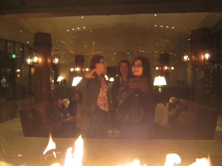 three women in an apartment at night, standing over the fire pit