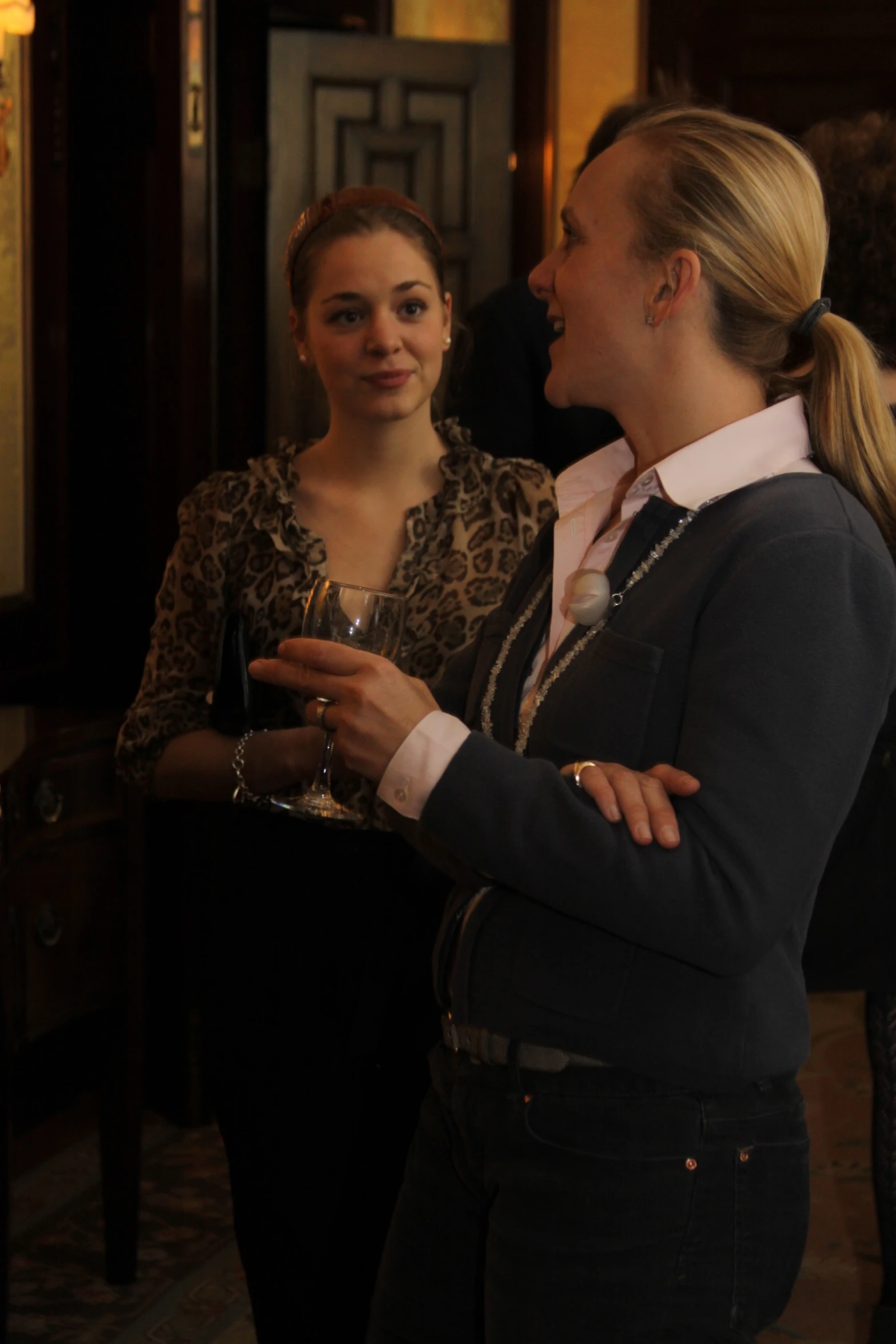 two pretty young women talking and laughing while holding drinks