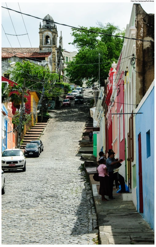 two people sit on the steps of a cobbled street