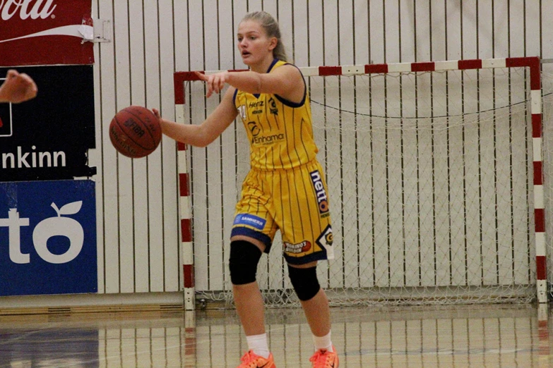 female basketball player holding a basketball in front of a goal