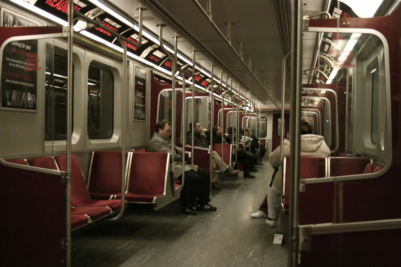 a train filled with red seats next to tall building