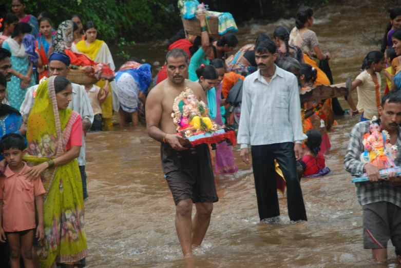 man carrying a cake while walking in flooded area