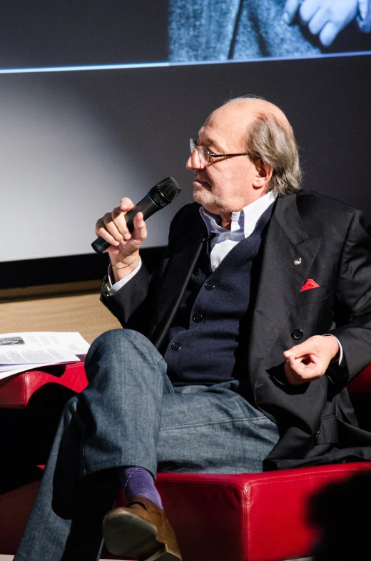 a man in suit and tie sitting down and talking