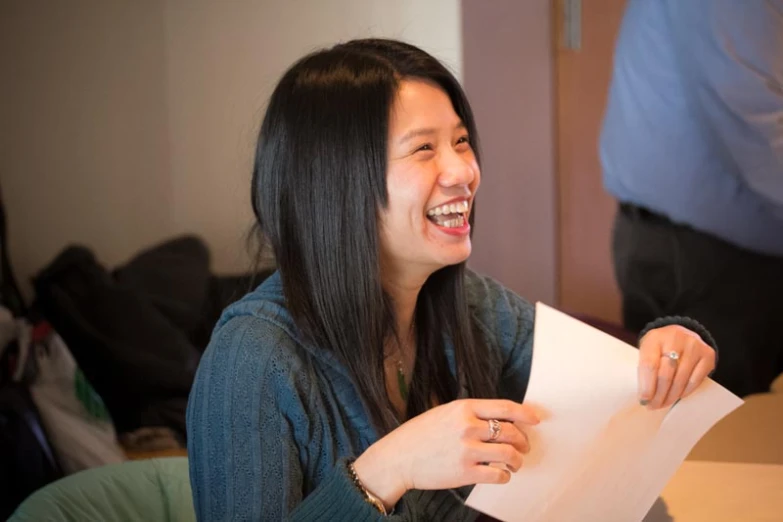 a woman smiling while holding a piece of paper