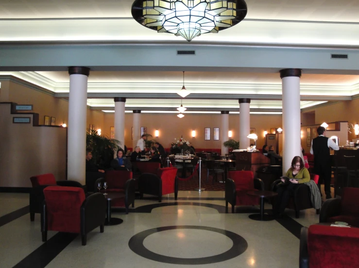 a couple sitting in red chairs on the inside of a lobby