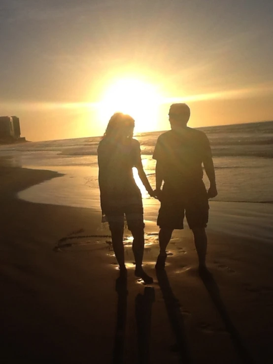 two people on a beach are holding hands