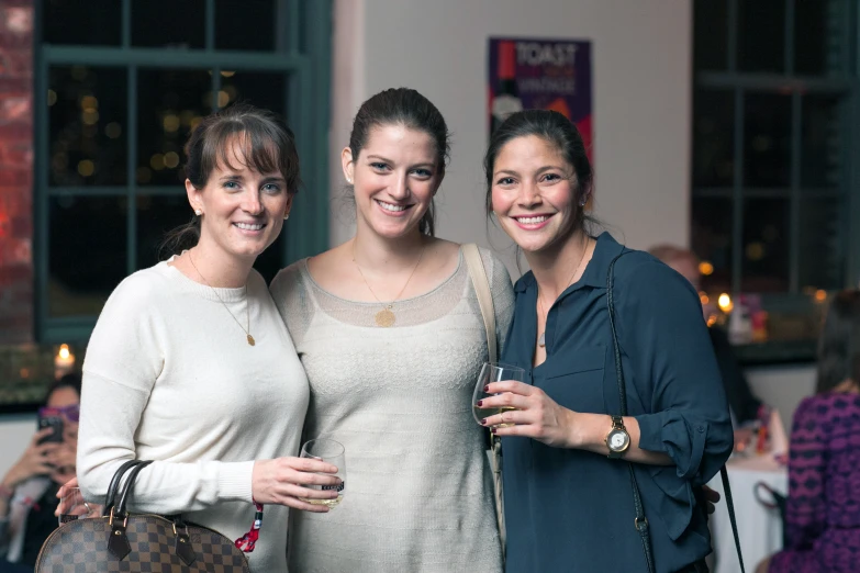 two women are holding a beer while posing for a po