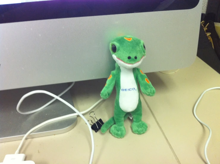 a stuffed animal next to the computer monitor