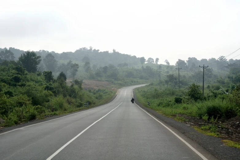 person walking across the road to a motorcycle