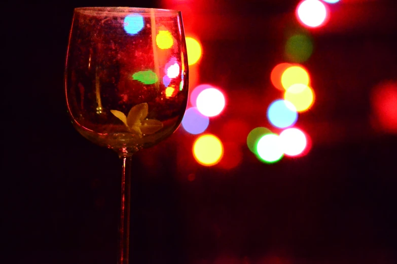 a goblet of wine sits next to an illuminated background