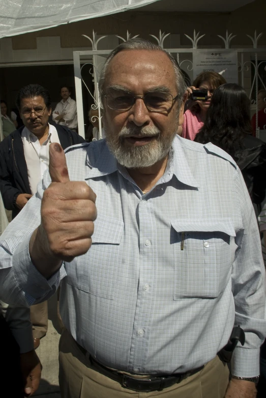a man with a white beard gives the thumbs up
