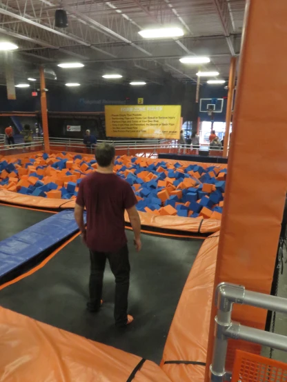 a man standing on top of a large orange and blue trampoline