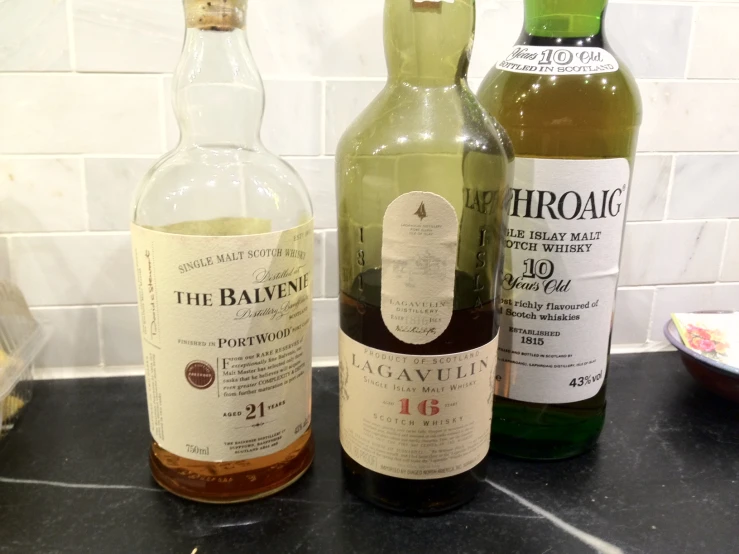three bottles of whisky sitting on a black counter