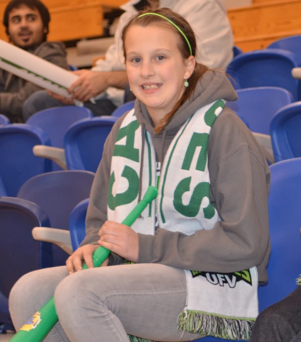 a girl with a baseball bat sitting on the side of a bleachers seat