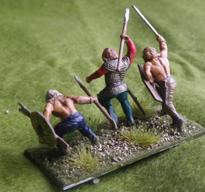 three figurines on a green cloth are holding swords