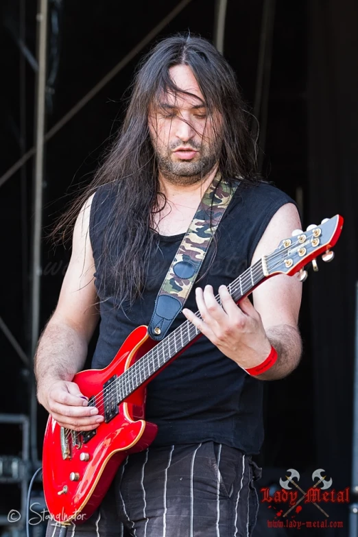 the man has long hair and holds an electric guitar