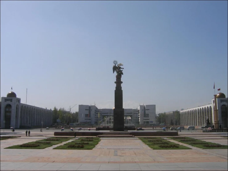 a large outdoor area with stone, brick and stucco features a large statue that has a bird on it in the center