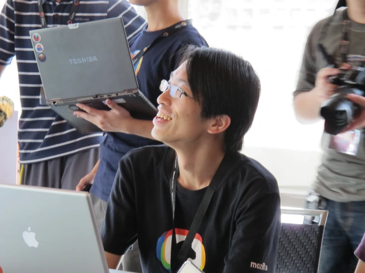 a boy holding an apple laptop up to his face