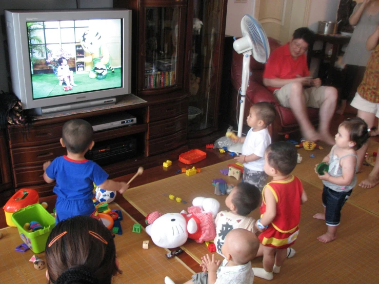 many children are playing with toys in front of the television