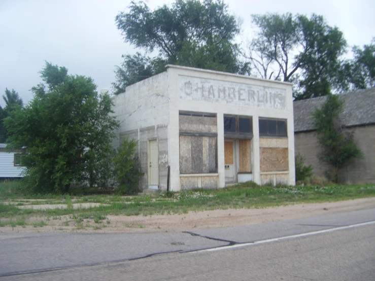 an abandoned building with a broken down window next to trees