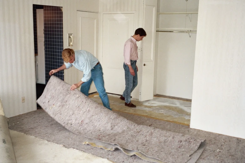 the two men are making a large rug in their living room