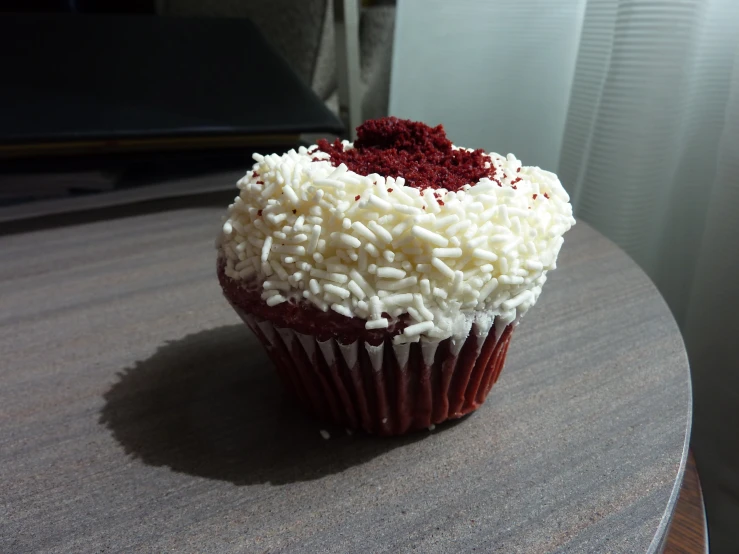 a red velvet cupcake topped with white frosting