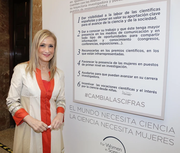 the smiling woman poses next to a sign