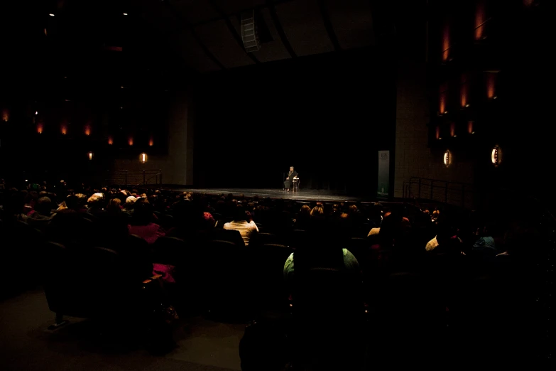 a dark room full of chairs and a stage with a woman on a stage