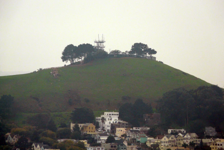 view of houses on top of hill with cellular tower in background