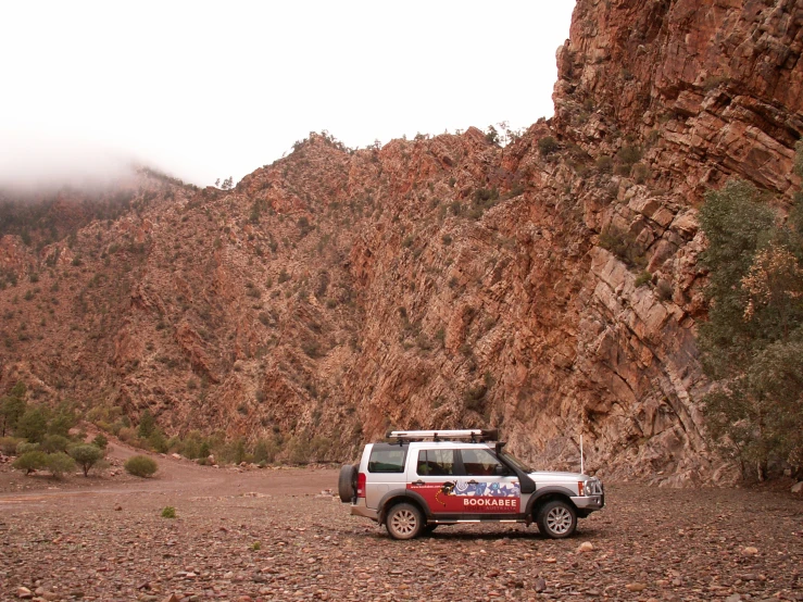 a truck is parked by a tall rocky mountain