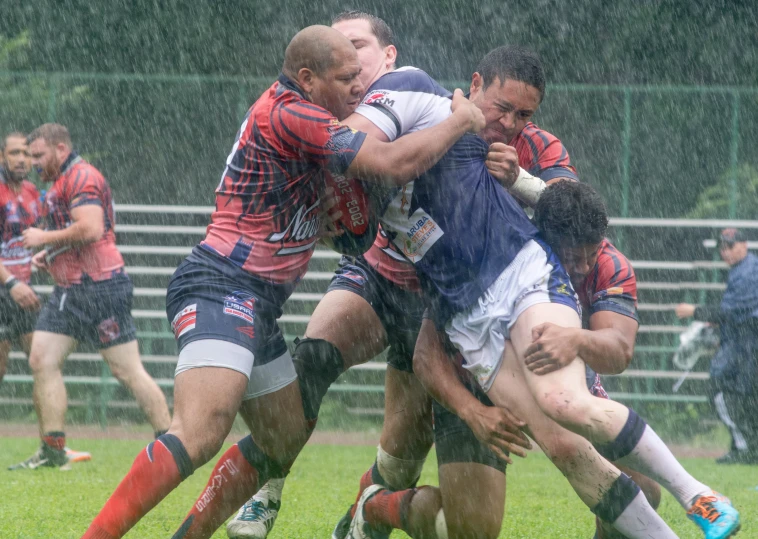 a group of men playing rugby on a wet grass field