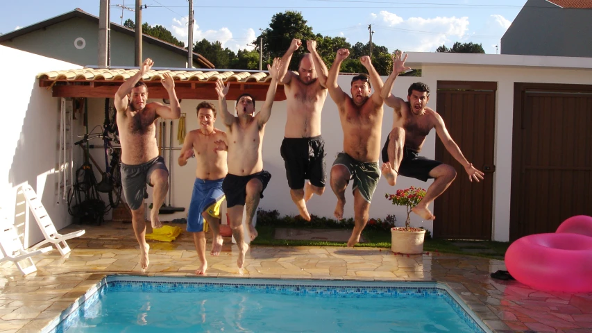 six young men jump into a pool for the camera