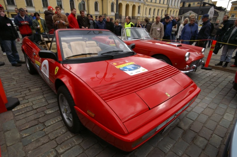 classic racing cars parked on the street in a crowd