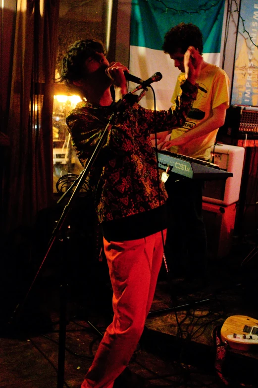 two men stand by the microphone while playing music