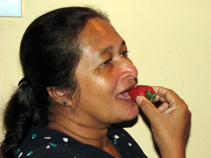 a woman holding an apple while she has a strawberry