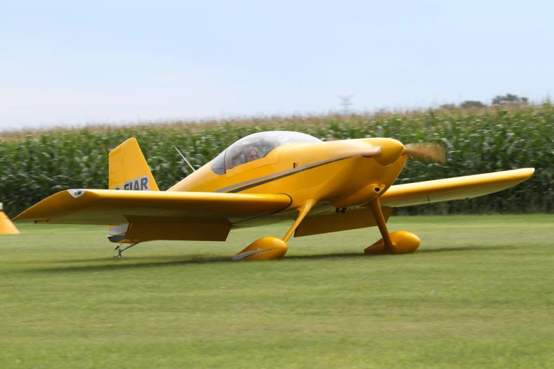 a small yellow plane sitting on top of a grass field